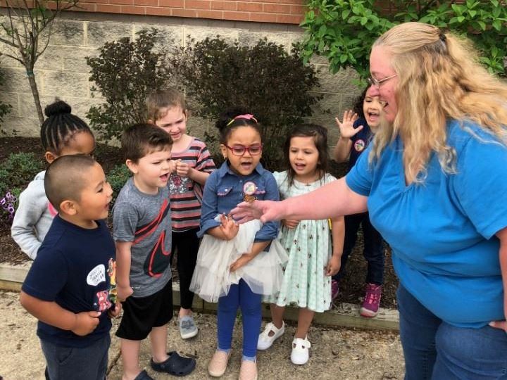 Preschool teachers with preschool students outside holding butterfly